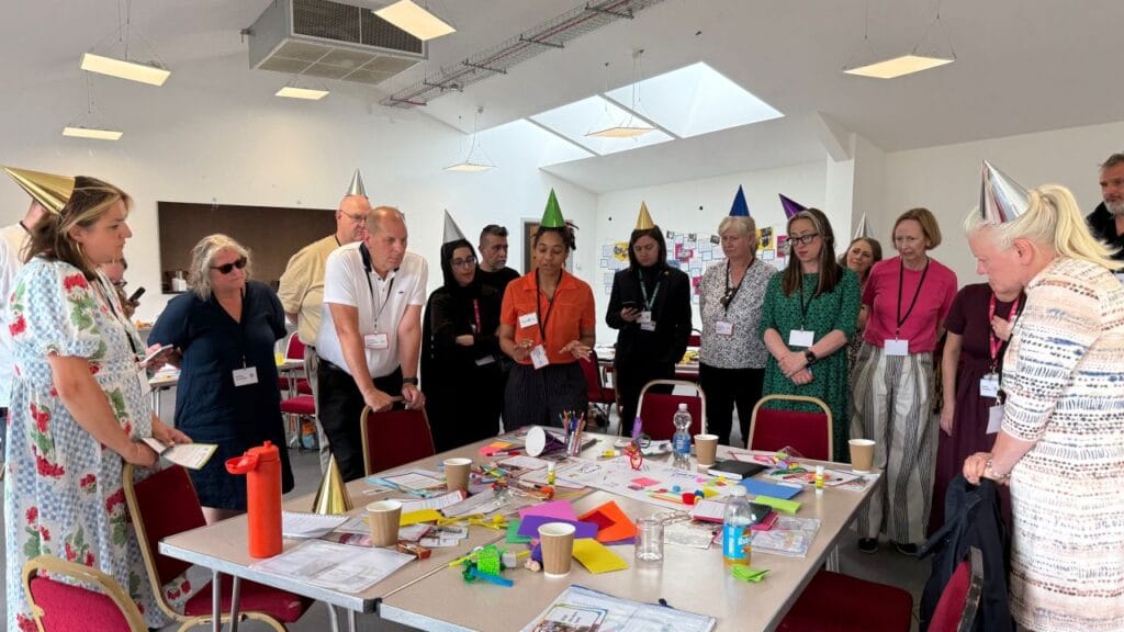 Participants gathered around a table during an interactive workshop, discussing ideas and taking part in a group activity using creative materials
